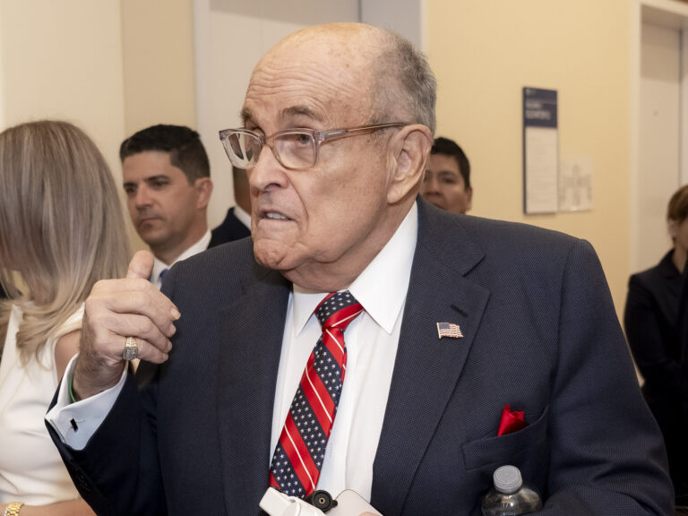 Photo shows former New York City mayor Rudy Giuliani, an older bald man in glasses anda blue suit.