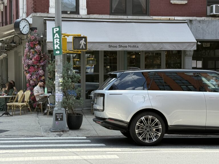 Image shows a restaurant with a grey awning and a Land Rover pared in front.