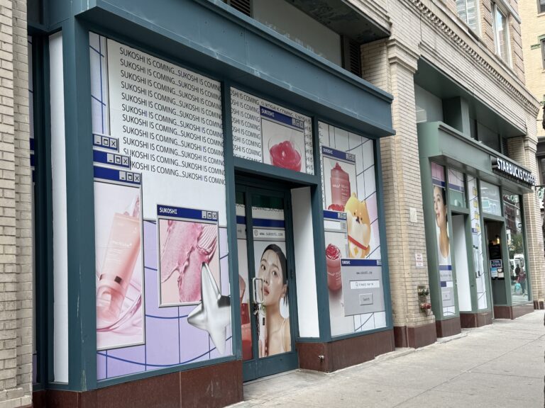 Image shows a storefront covered in advertisements for an Asian beauty brand.