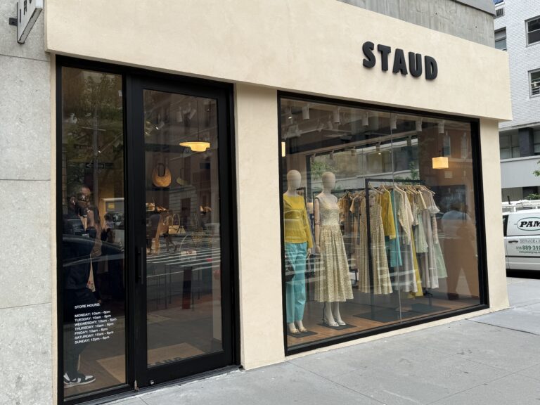 Photo shows a beige storefront for a luxury clothing brand 'Staud.'