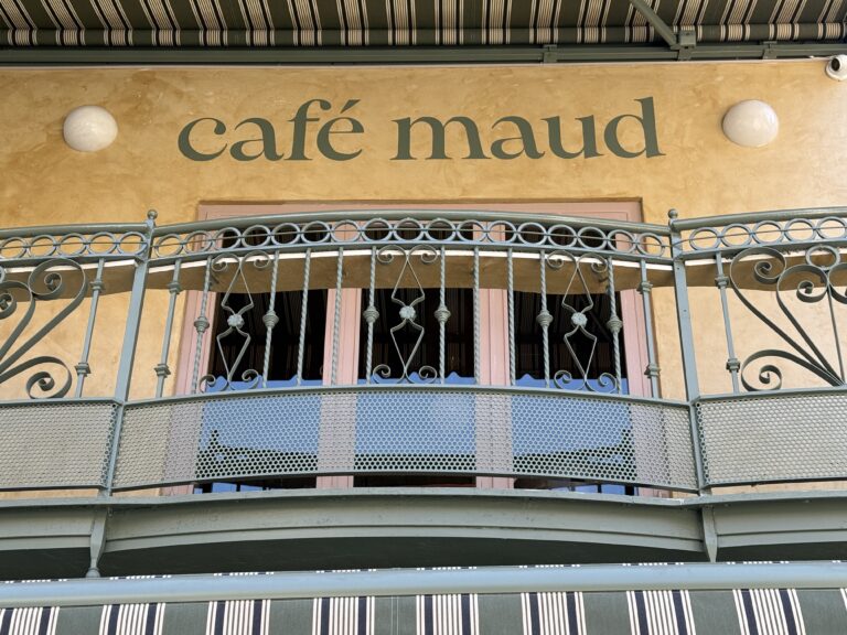 Photo shows a beige building with "cafe maud" painted on the side.