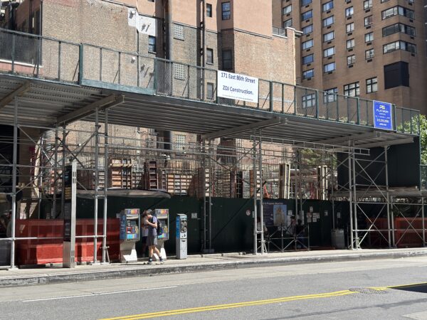Photo shows a bus stop in front of a construction site.