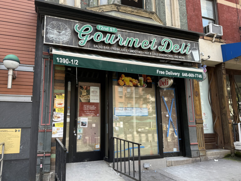 Photo shows a defunct deli with papered over windows.
