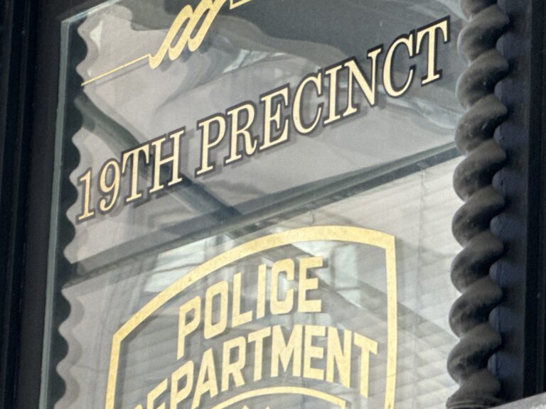 Photo shows a sign in a window reading "19th Precinct Police Department"