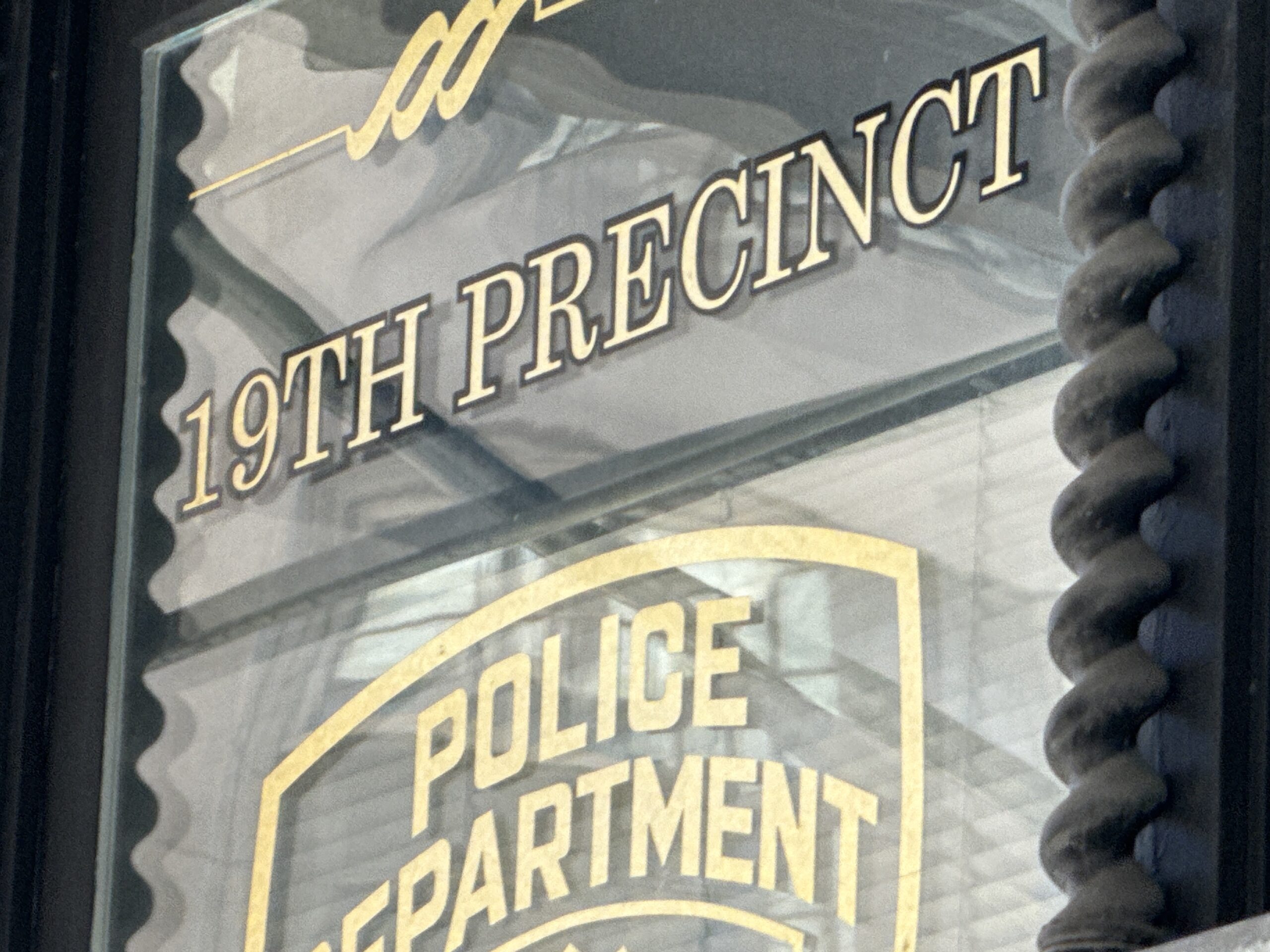 Photo shows a sign in a window reading "19th Precinct Police Department"
