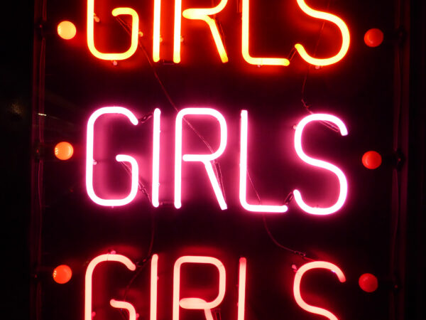 Photo shows three neon signs reading "Girls Girls Girls."